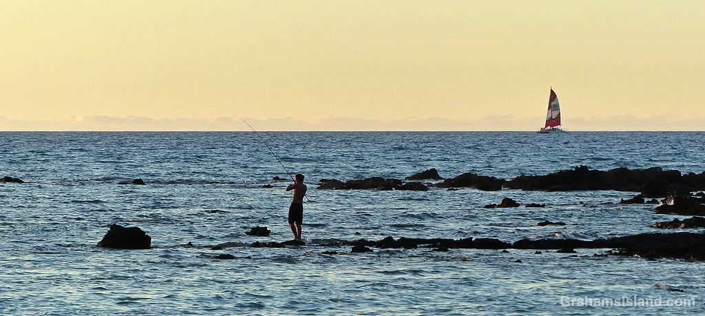 A fisherman reels in his line on the South Kohala coast